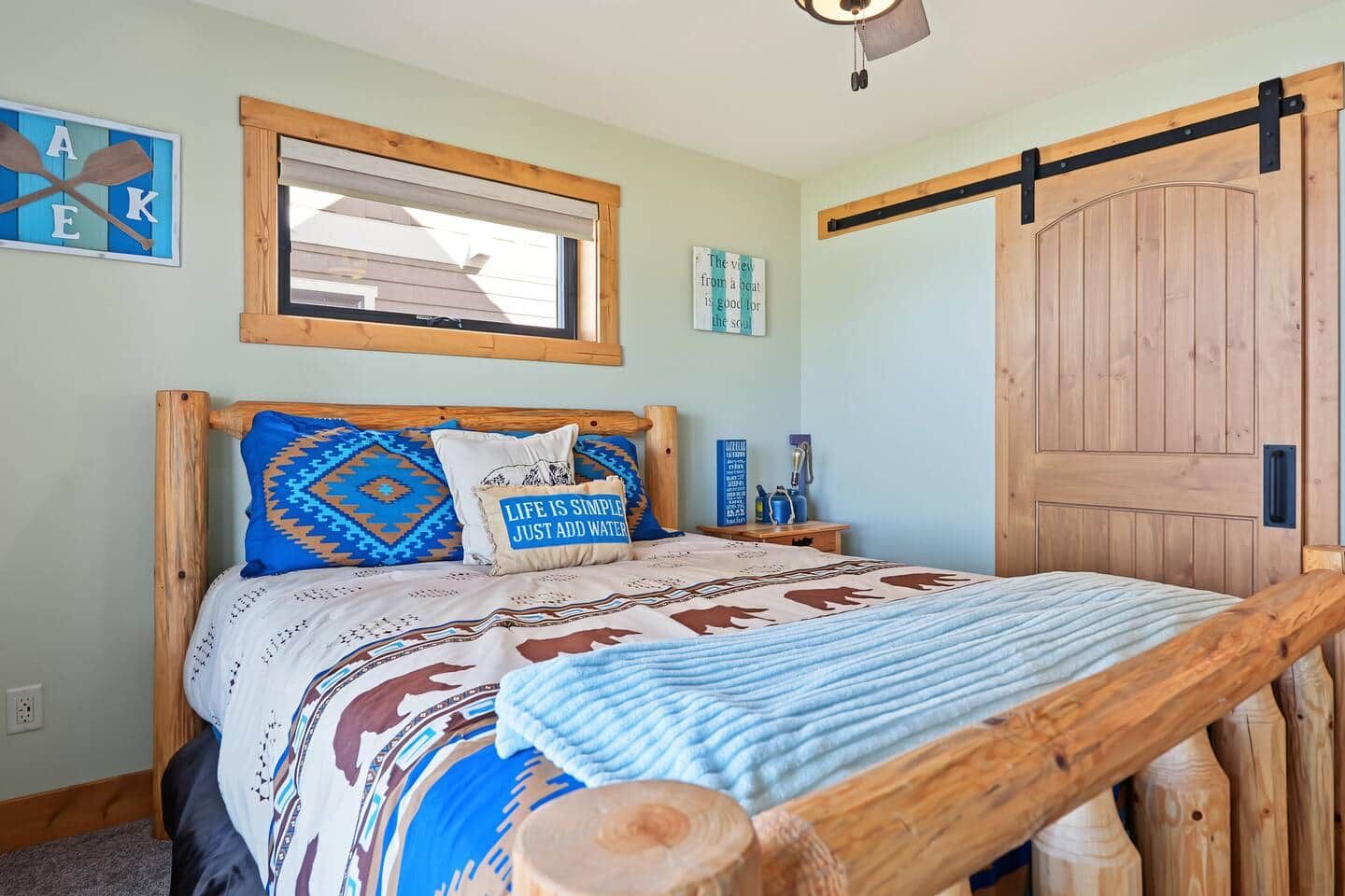 Una camera da letto con un letto con struttura in legno, una finestra con persiane e una vista da cartello che indica un’imbarcazione, oltre a una porta in legno.