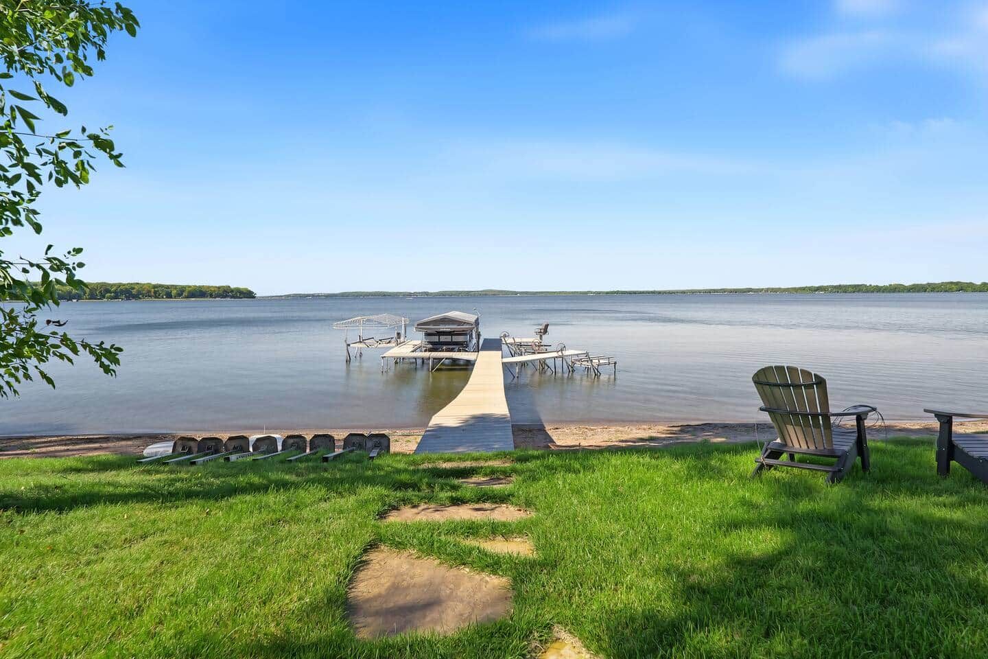 A lakeside dock with a boat house, a chair, and a row of canoes.
