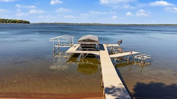 A dock extending into a calm lake with a covered structure and seating area.