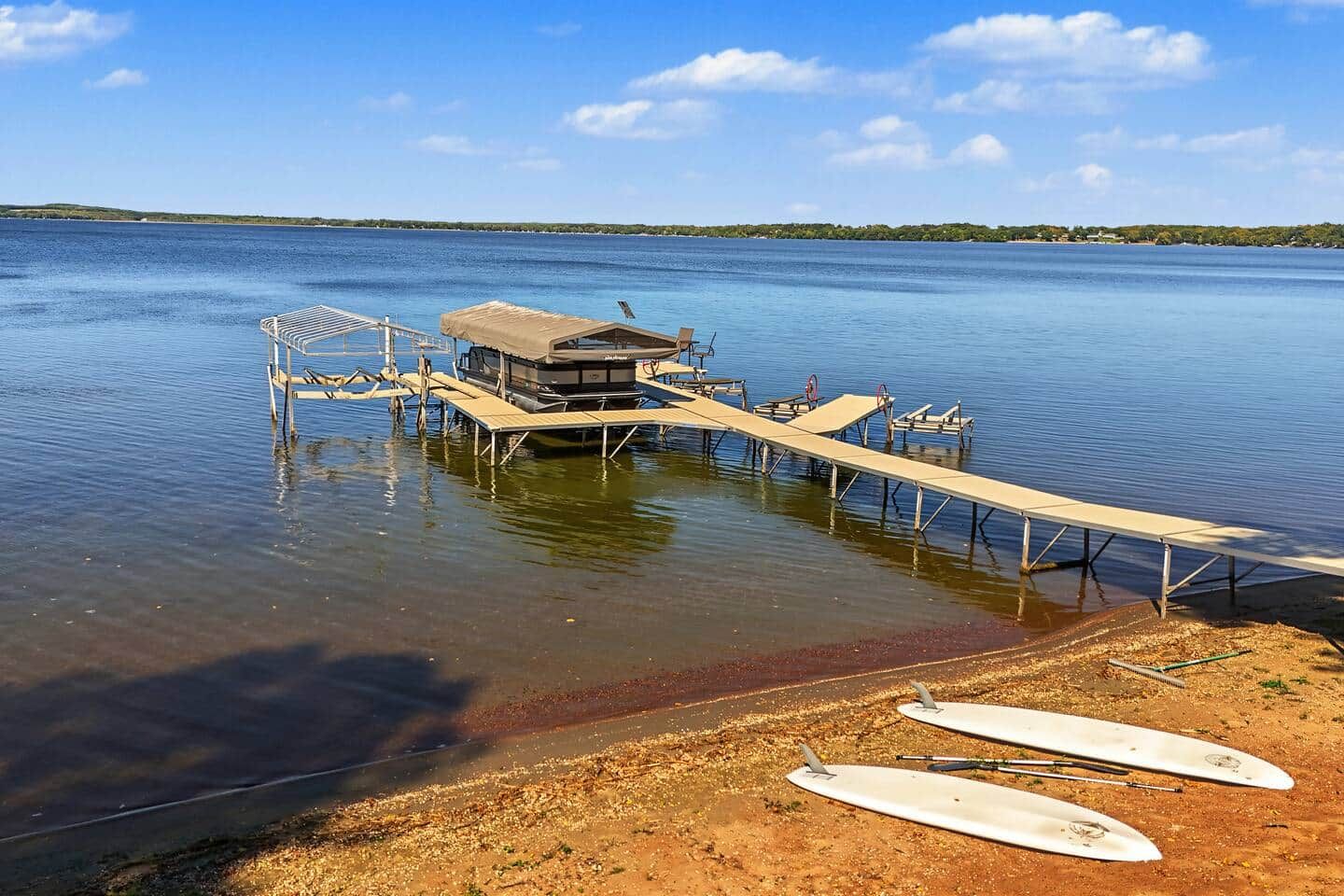A dock extending into a calm body of water with a small building on it, surrounded by clear skies.