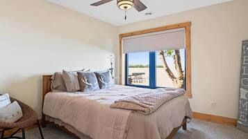 A bedroom with a bed, a ceiling fan, a window with a view, and a welcome sign.