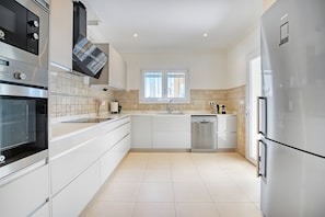 A modern kitchen with stainless steel appliances, a window, and a tiled backsplash. - Villa 'Vera' with sea view, Wi-Fi, heated pool and air conditioning (Balcó al Mar)