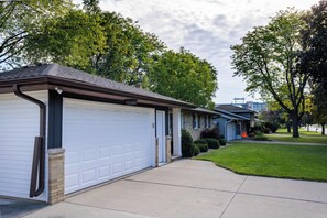 A residential garage with a white garage door, a brick foundation, and a metal gutter. - Walking distance to Lambeau Field- Dog Friendly! (Green Bay)