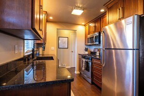 A modern kitchen with stainless steel appliances, wooden cabinets, and a granite countertop. - Walking distance to Lambeau Field- Dog Friendly! (Green Bay)