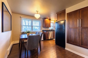 A kitchen with wooden cabinets, a stainless steel refrigerator, and a dining area with a table and chairs. - Walking distance to Lambeau Field- Dog Friendly! (Green Bay)