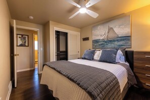 A bedroom with a bed, a ceiling fan, a painting of a sailboat, a closet, and a hallway. - Walking distance to Lambeau Field- Dog Friendly! (Green Bay)