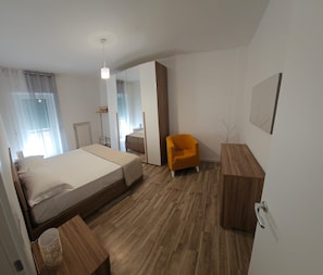 A modern bedroom with a bed, a chair, a bedside table, a mirror, and a wardrobe. - La Dimora Di Mari—10 minutes from Sassi—easy parking—Wi-Fi (Matera)