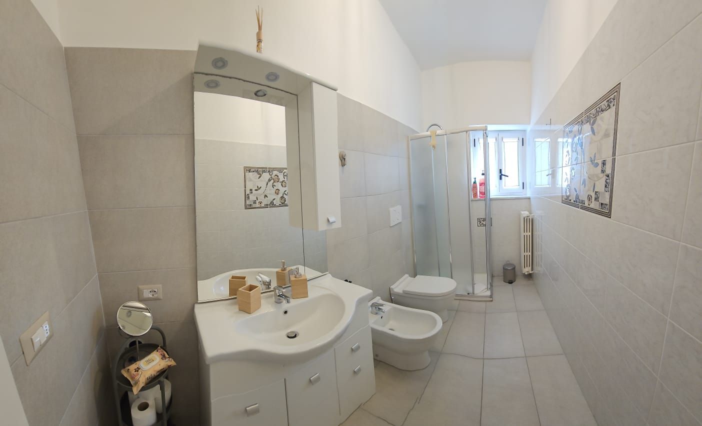 A modern bathroom with a sink, mirror, toilet, bidet, and shower.