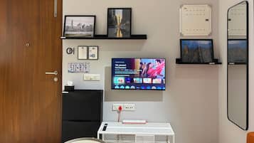 Una habitación con una televisión mostrando una película, una puerta y una pequeña mesa con un control remoto.