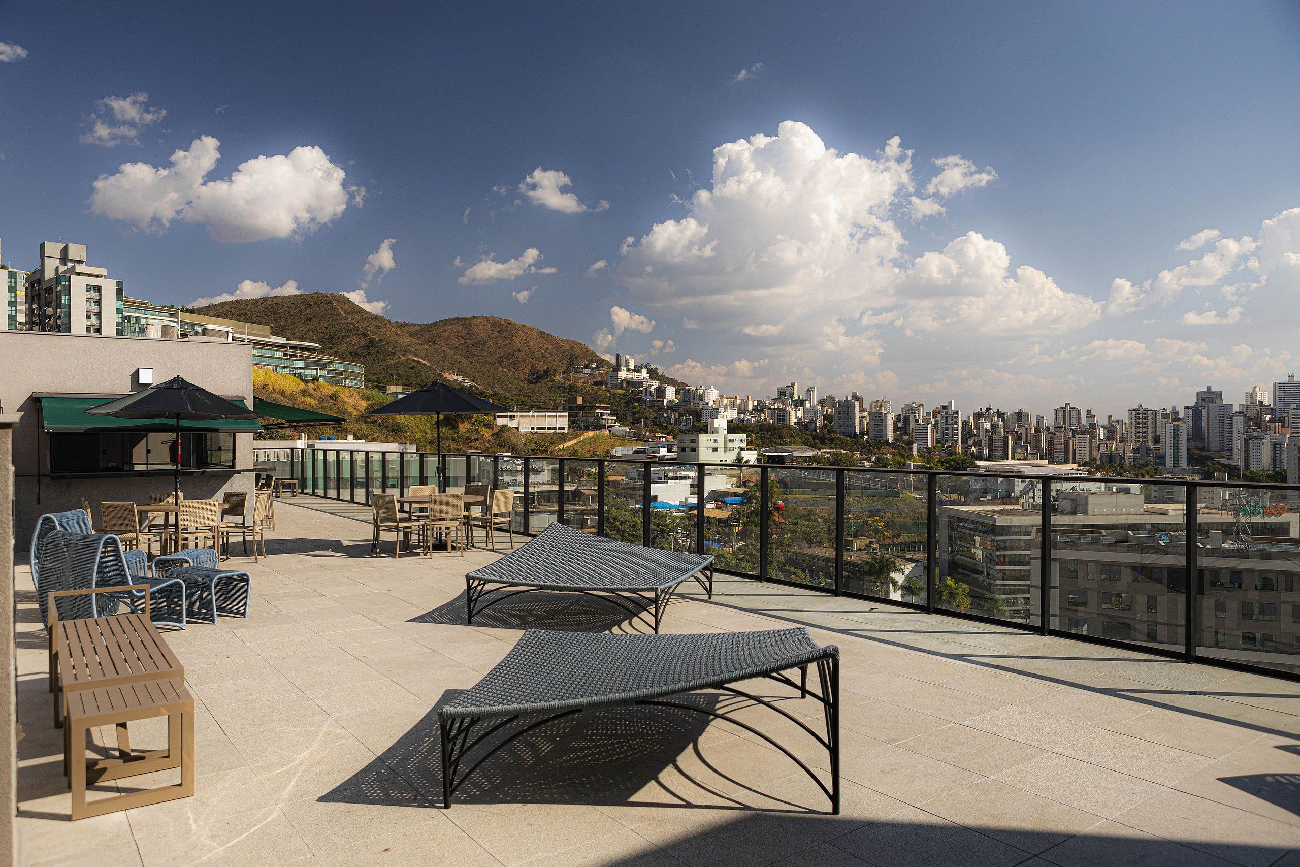 Une terrasse sur le toit avec des sièges extérieurs, une vue sur le paysage urbain et une montagne en arrière-plan.