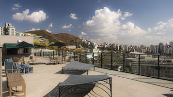 Une terrasse sur le toit avec des sièges extérieurs, une vue sur le paysage urbain et une montagne en arrière-plan.