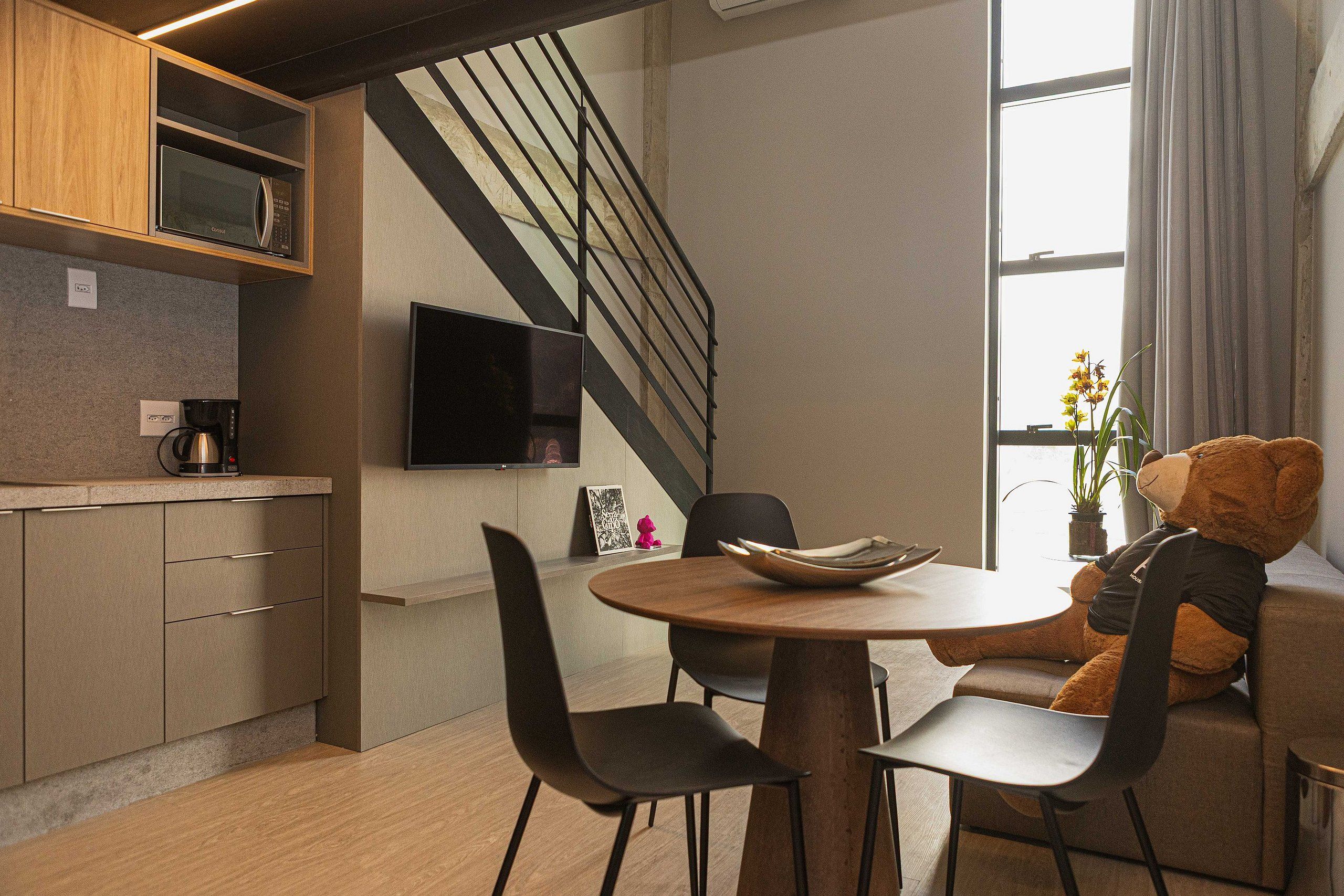 A modern kitchen with a built-in microwave, a coffee machine, and a flat-screen TV.