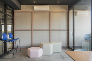 A modern waiting area with a seating arrangement, a partition wall, and an air conditioning unit.