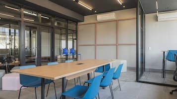 A conference room with a long table, blue chairs, and glass walls.