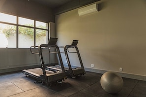 A gym with treadmills, a stationary bike, and a large exercise ball. - Housi Delphos (Belo Horizonte)