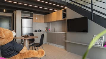 A modern kitchen with a built-in refrigerator, a dining area with a table and chairs, and a flat-screen TV mounted on the wall.