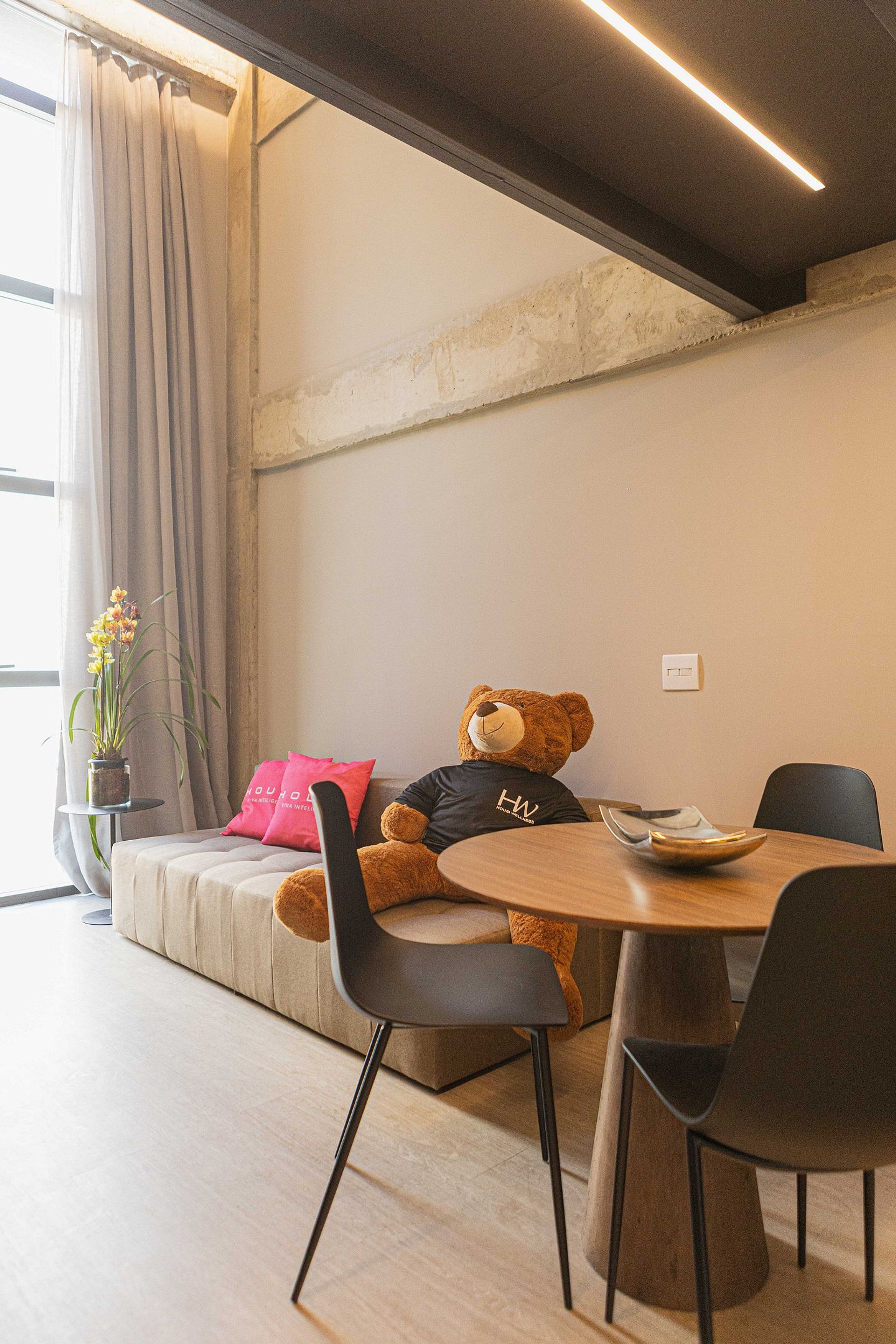 Una habitación acogedora con un sofá, una mesa de comedor y un osito de peluche.