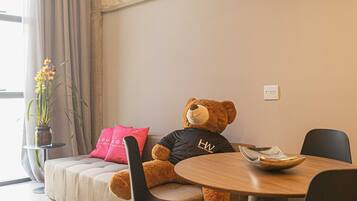 Una habitación acogedora con un sofá, una mesa de comedor y un osito de peluche.