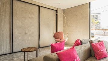 A modern living room with a sofa, a hanging chair, and a small table.