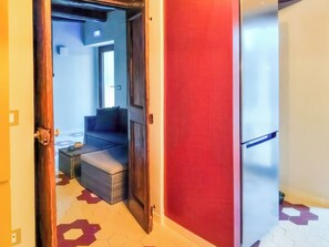 A room with a sofa, a small table, and a refrigerator. - Casa Cecilia (Maratea)