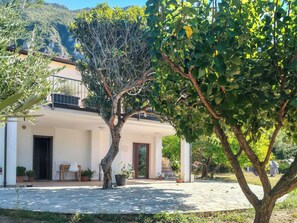 A building with a patio area, potted plants, and a view of a mountainous landscape. - Casa Cecilia (Maratea)