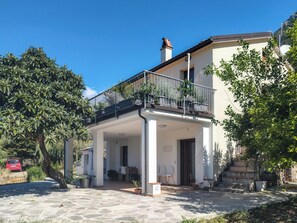 A two-story building with a balcony, outdoor seating area, and a stone-paved entrance. - Casa Cecilia (Maratea)