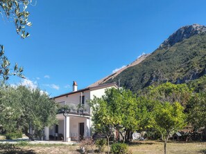 A two-story building with a balcony, surrounded by trees and a mountain backdrop. - Casa Cecilia (Maratea)