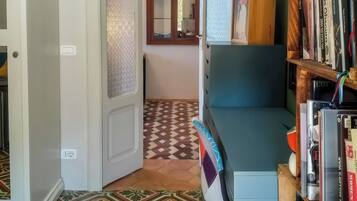 A hallway with patterned floor tiles, a bookshelf with books, and a door leading to another room.