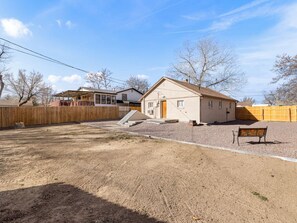 Una propiedad residencial con camino de grava, cerca de madera y una casa de un piso.