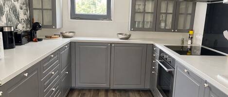 A kitchen with grey cabinets, a window, and a built-in oven.