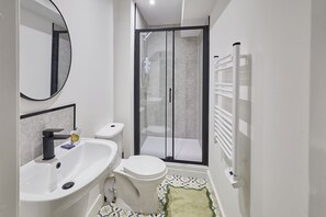 Un baño moderno con inodoro, lavamanos y ducha.
