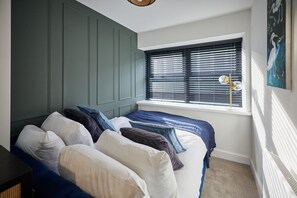 Ein Schlafzimmer mit einem Bett, Kissen, einem Fenster mit Jalousien und einem Bild an der Wand.