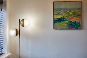 Eine Stehlampe mit zwei kugelförmigen Lampenschirmen und einem Bild an der Wand.