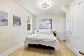 A bedroom with a bed, a window, a door, and artwork on the walls. - Urban Oasis w/ 10 beds•Sauna•Solar•Wellness Studio•Fenced Yard•Garage (Falcon Heights)