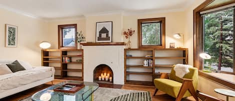 A living room with a fireplace, a sofa, a coffee table, and a bookshelf.