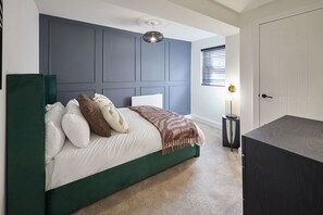 A bedroom with a green bed, white bedding, a grey headboard, a bedside lamp, and a window with blinds. - Host & Stay - The Premier Loft (Middlesbrough)