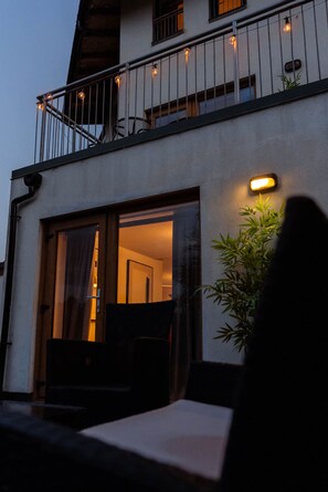 A modern building with a balcony, large windows, and a potted plant. - Lochburn House | Garden, Parking & Stylish 3BR (Glasgow)