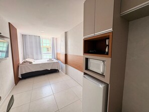 A hotel room with a bed, a built-in TV, a microwave, and a small kitchenette. - Eco Mirage Residence por YOLO (Ipojuca)