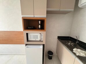 A compact kitchenette with a microwave, coffee maker, and a small refrigerator. - Eco Mirage Residence por YOLO (Ipojuca)
