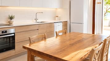 A modern kitchen with a wooden table and chairs, a built-in oven, and a dishwasher.