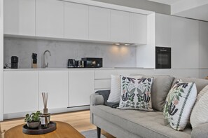 A modern kitchen with white cabinets, a coffee machine, and a microwave. - Balcony 2-bed Apartment Near Albert Park (Melbourne)