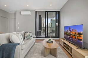 A modern living room with a sofa, coffee table, and a flat-screen TV. - Balcony 2-bed Apartment Near Albert Park (Melbourne)