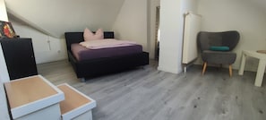 A bedroom with a bed, a chair, a small table, and a radiator. - Vrbo Property (Euskirchen)