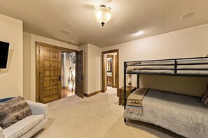 Una habitación con una cama litera, un sofá, una puerta de madera y un pasillo que conduce a otra habitación.