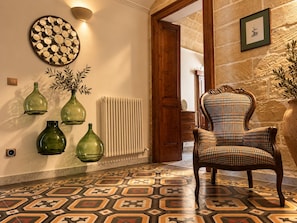 A room with a patterned floor, a chair, a wall clock, and a radiator. - LIVING IN Ástricu (Lecce)