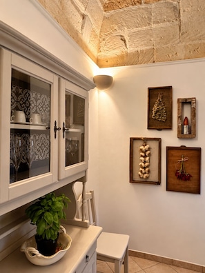 A kitchen with a white cabinet, a potted basil plant, and a white bench. - LIVING IN Ástricu (Lecce)