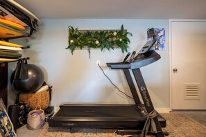 A home gym with a treadmill, exercise balls, and a wall-mounted plant. - The Breakers Paradise - New Listing (Carolina Beach)