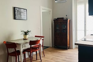Ein Essbereich mit Tisch, Stühlen, einer Topfpflanze, einem Holzschrank und einer Tür.