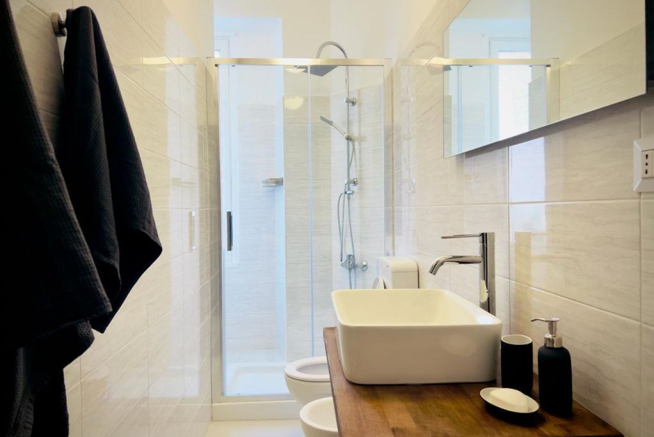 A modern bathroom with a glass-enclosed shower, a white sink, and a wooden countertop.