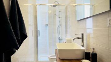 A modern bathroom with a glass-enclosed shower, a white sink, and a wooden countertop.